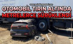 Otomobil, tırın altında metrelerce sürüklendi
