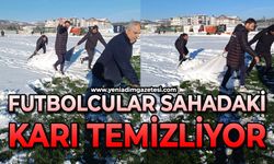 Maç öncesi futbolcular sahadaki karı temizliyor